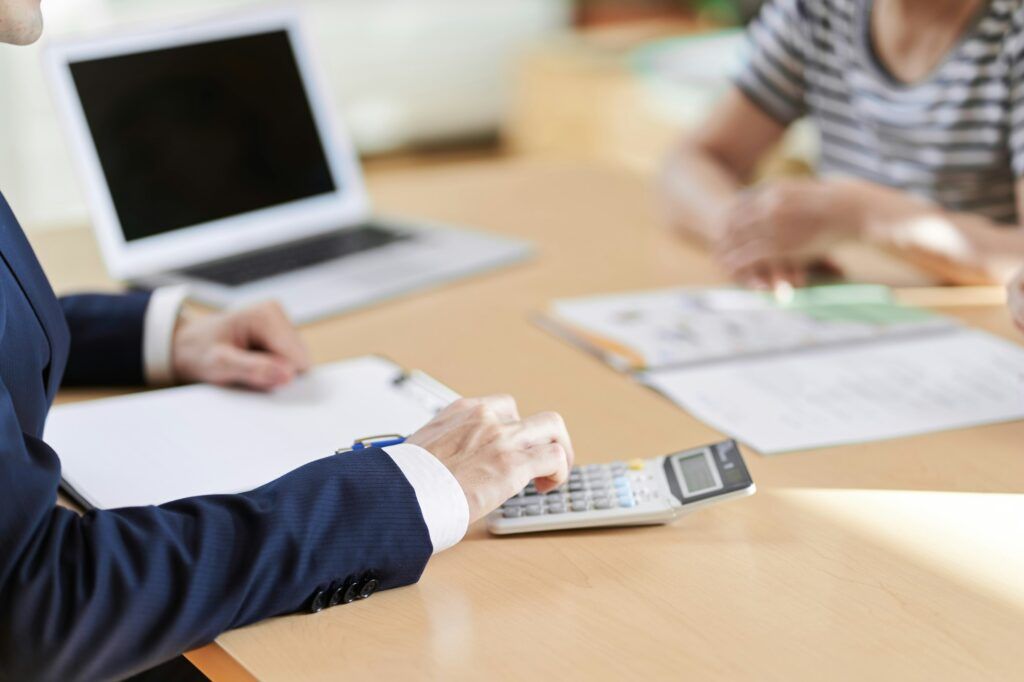 At hand of the insurance salesman who calculates with a calculator